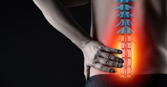 A man's back with a digital overlay of his spinal cord with highlights in red.